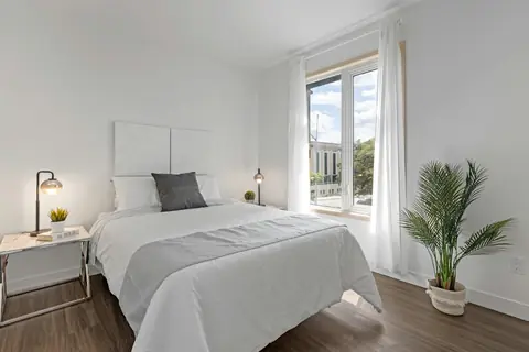 Bedroom with white bedding next to a window